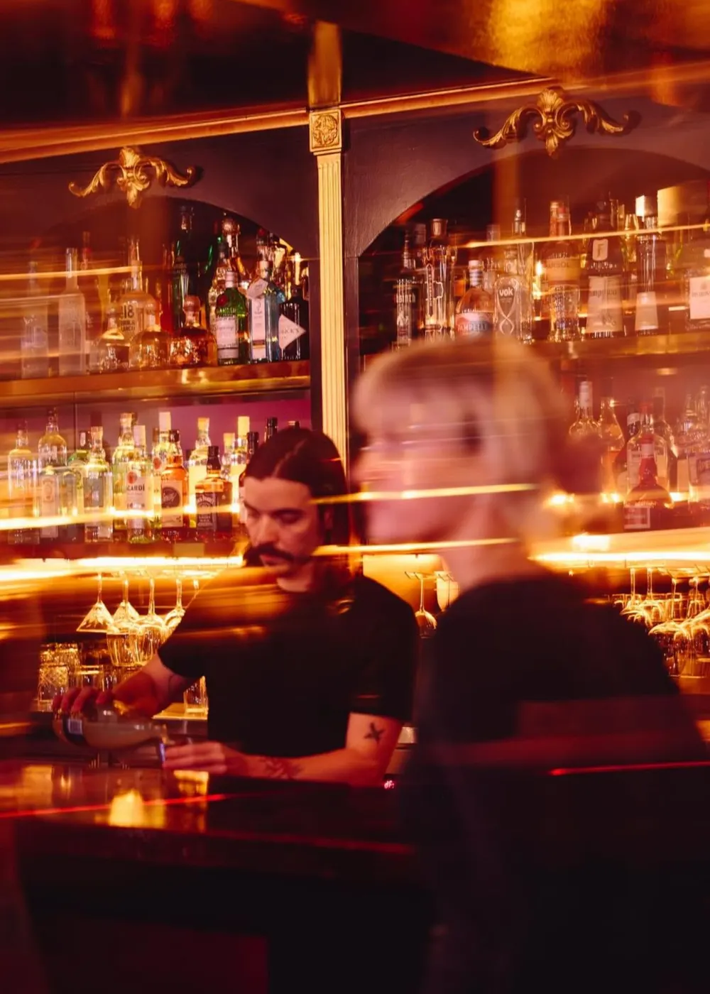 Bartender mixing drinks behind a busy bar