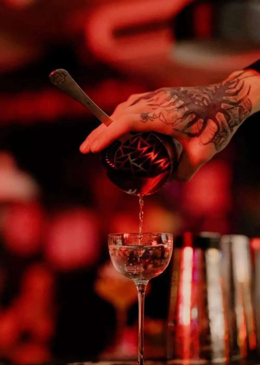 Bartender straining a cocktail into a coupe glass