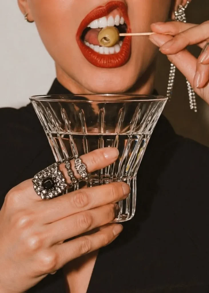 Woman with red lipstick holding a martini glass and an olive