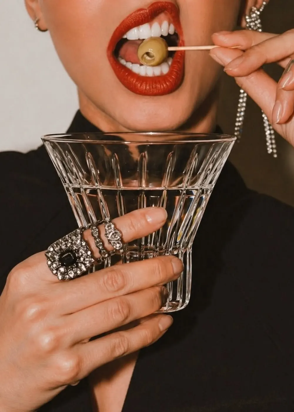 Woman with red lipstick holding a martini glass and an olive